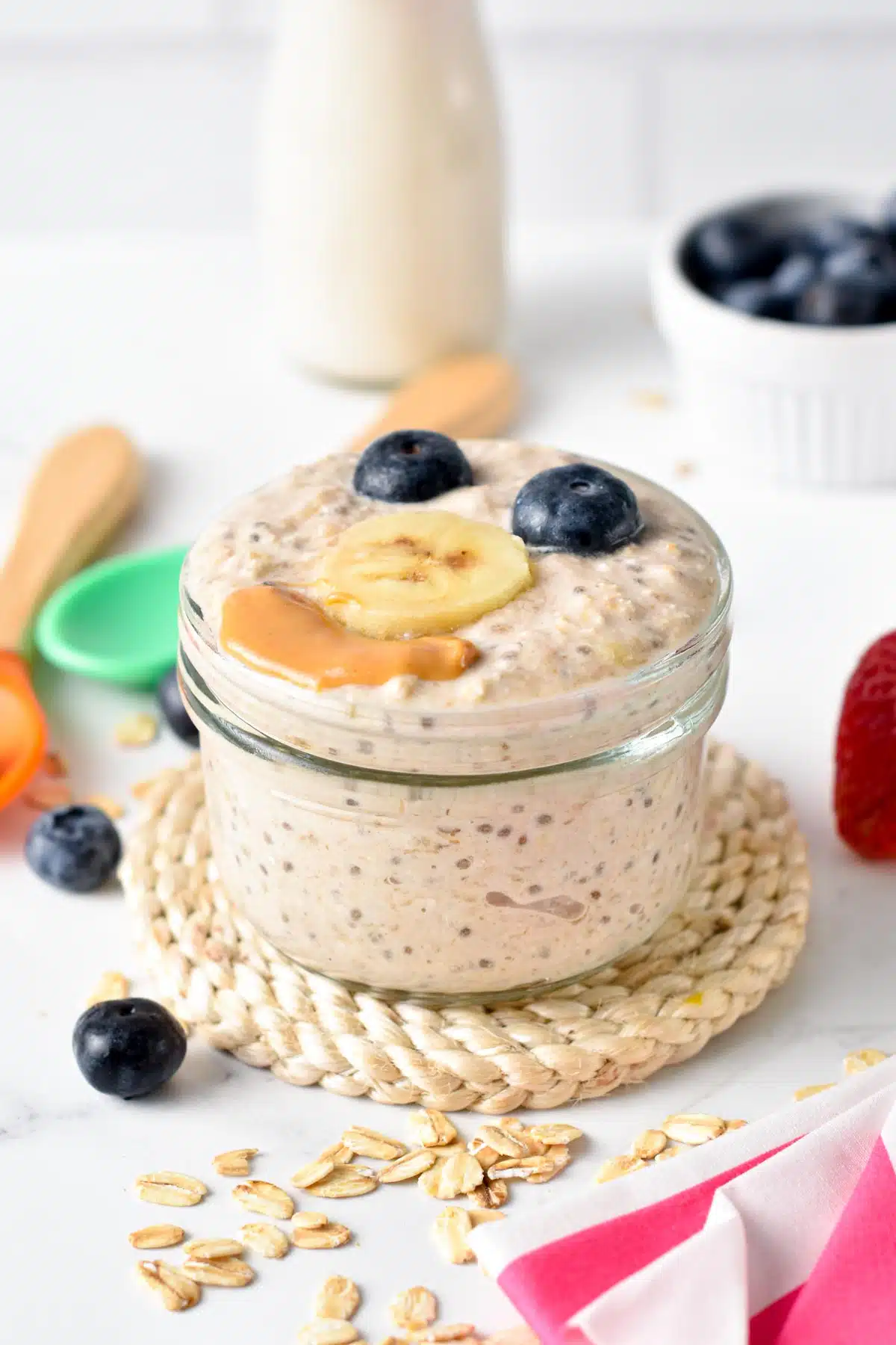 a glass jar filled with Overnight Oat for Baby topped with banana blueberries and peanut butter
